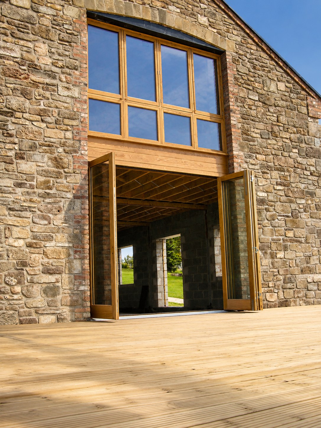 Tall timber-framed glazed opening in a stone barn