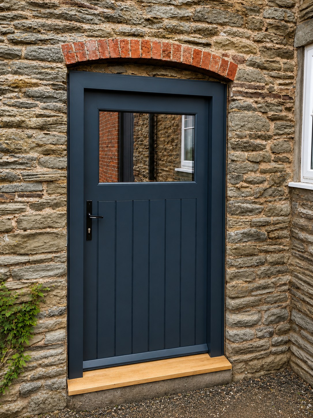 Dark painted entrance door in a stone opening