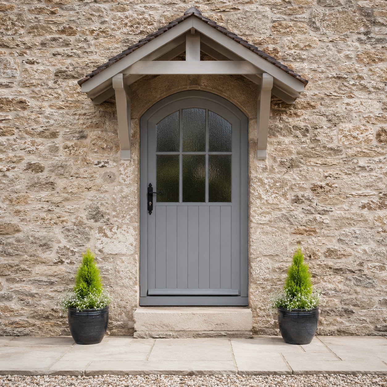 Grey glazed entrance door below a small pitched canopy