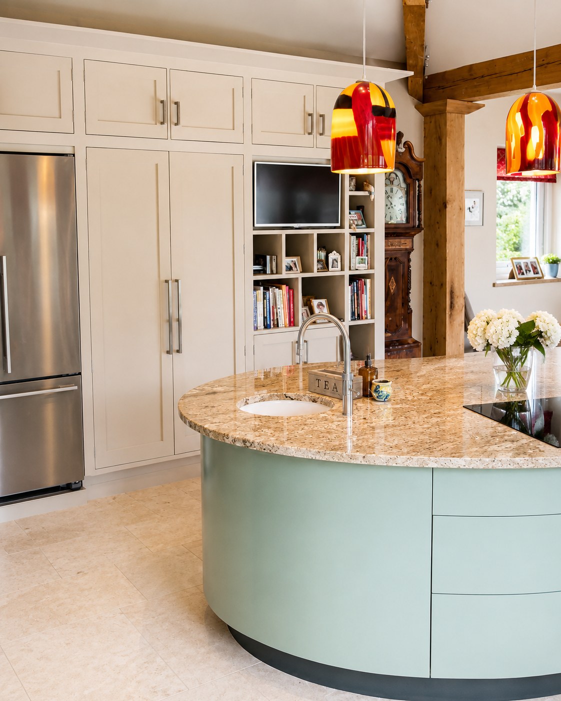 Curved kitchen island beside painted cabinets