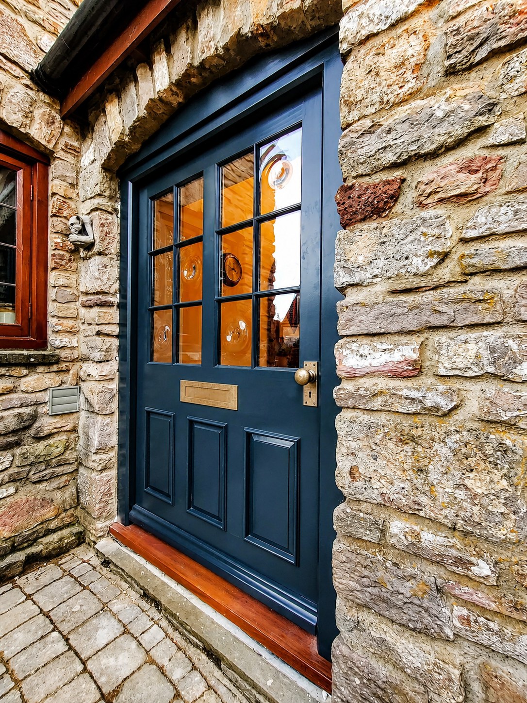 Dark glazed entrance door in a stone reveal