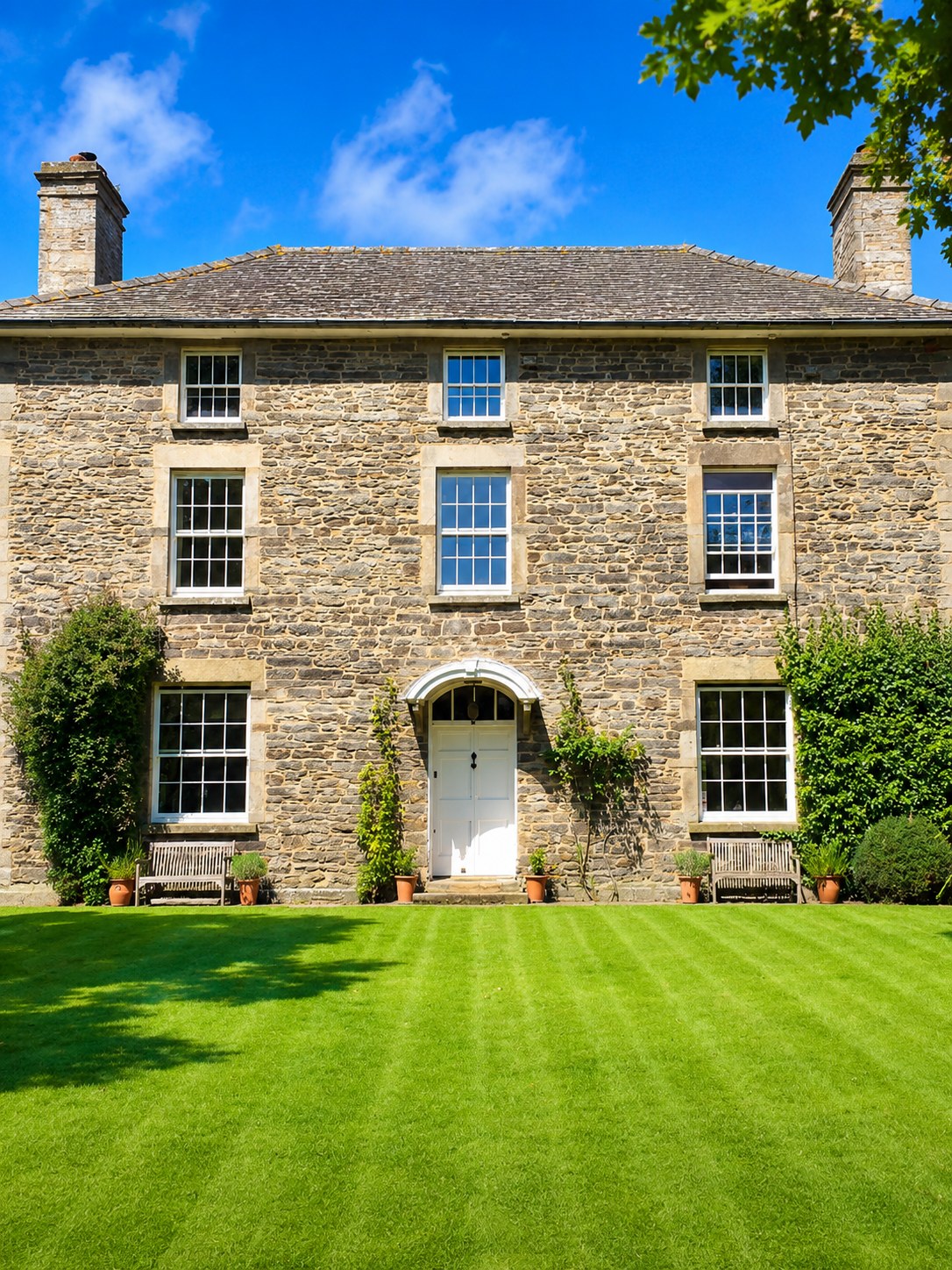 Stone house with painted windows and formal lawn