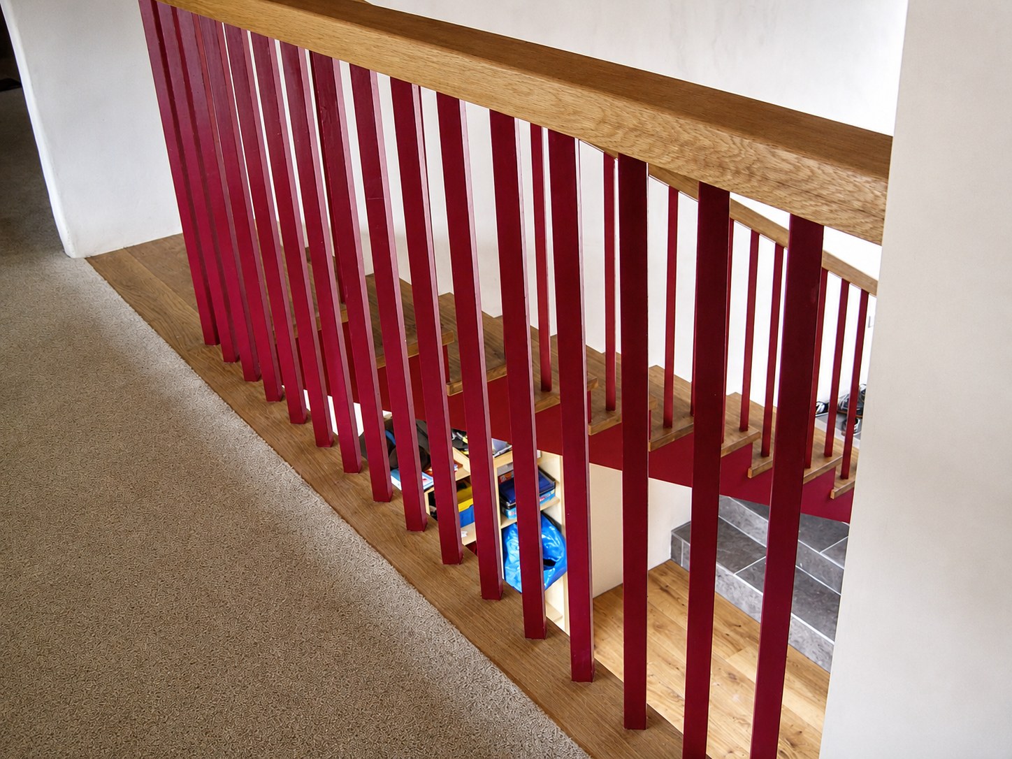 Timber handrail and red-painted balusters on a landing