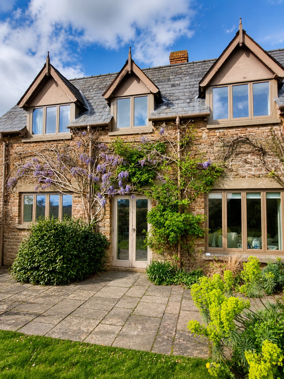 Stone house with timber dormers and garden-facing glazing