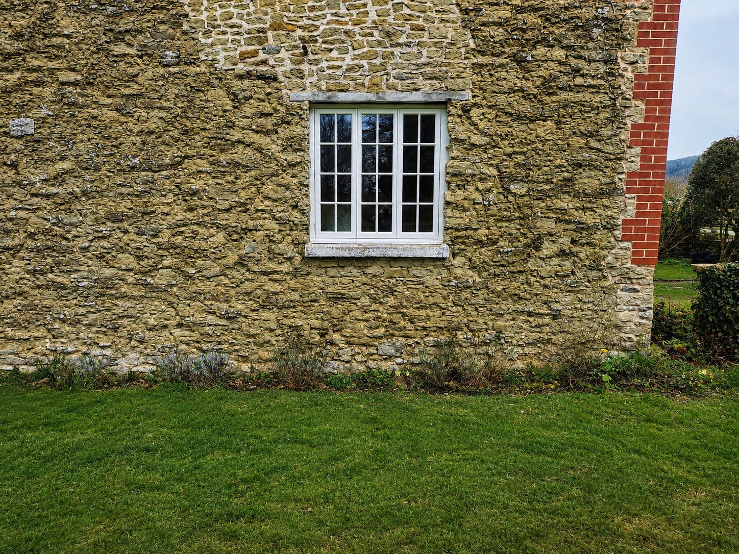 Divided-light white window in a stone elevation
