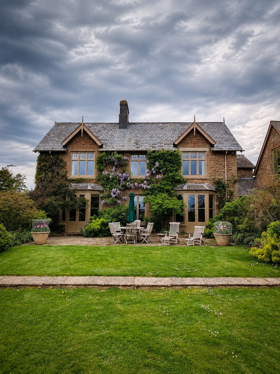 Stone house with timber dormers overlooking a lawn