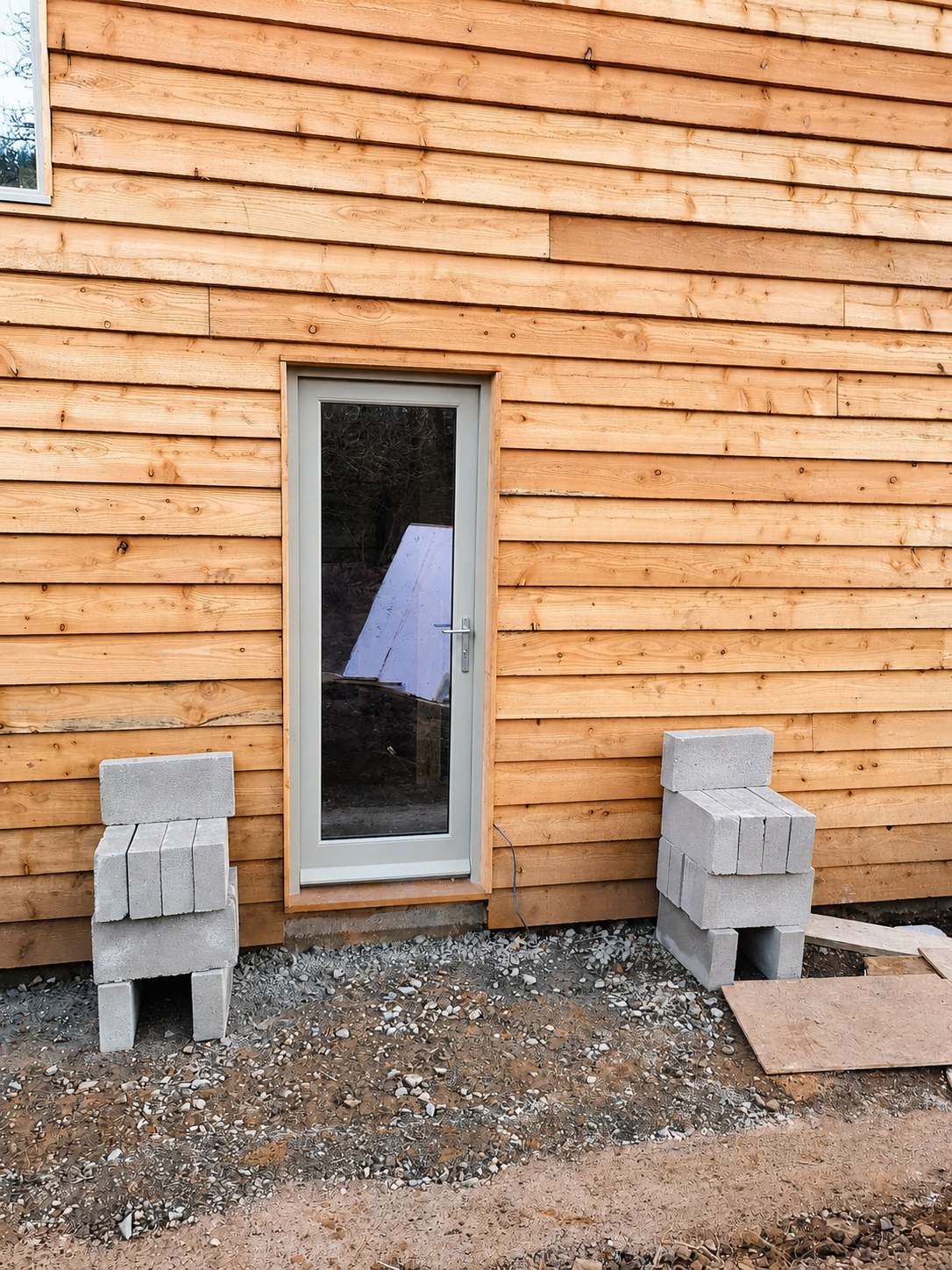 Grey glazed door set into timber cladding