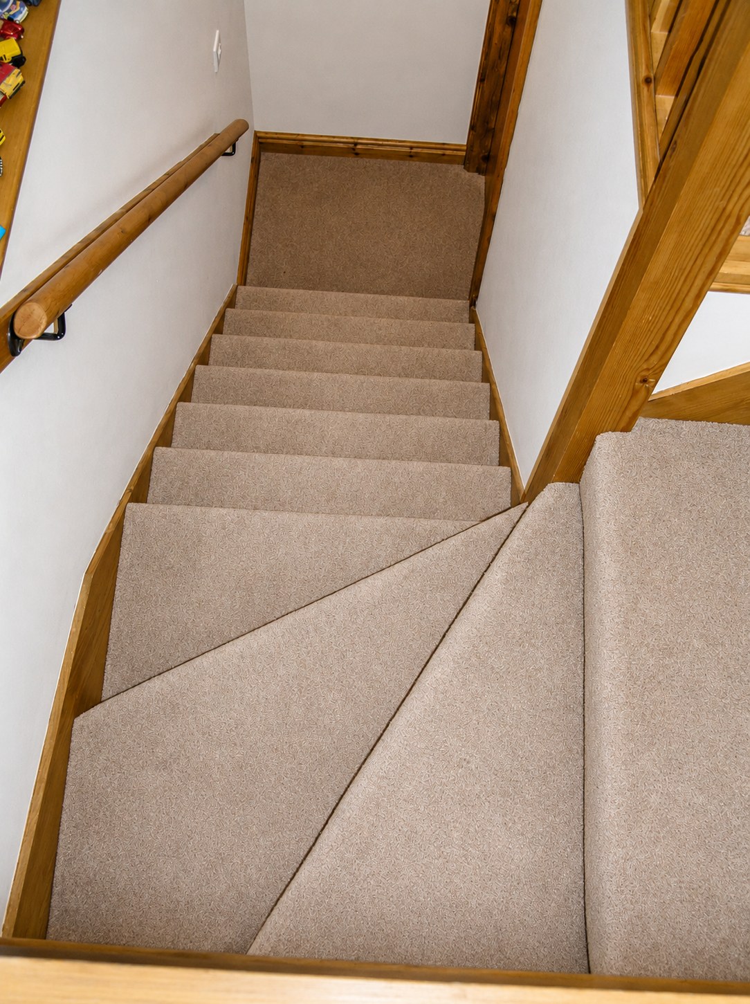 Carpeted stairs with a timber handrail