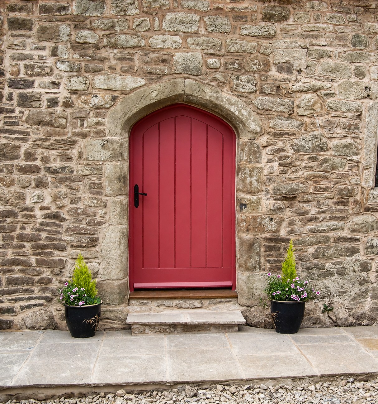 Arched red-painted boarded door in a stone wall