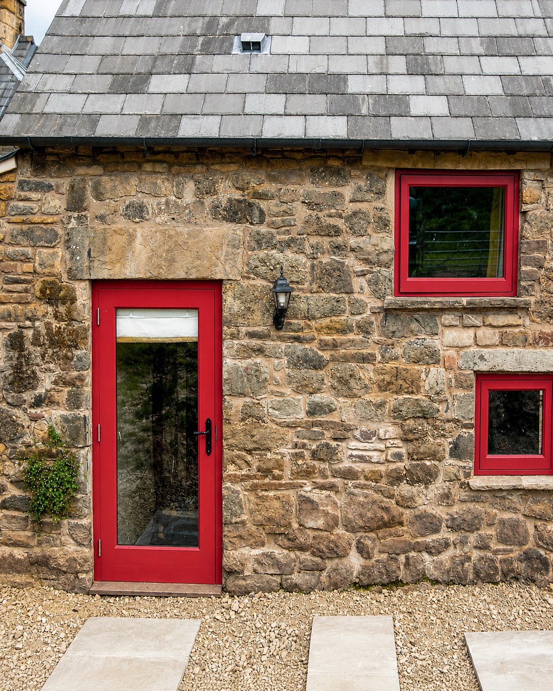 Red-painted door and windows in a stone outbuilding