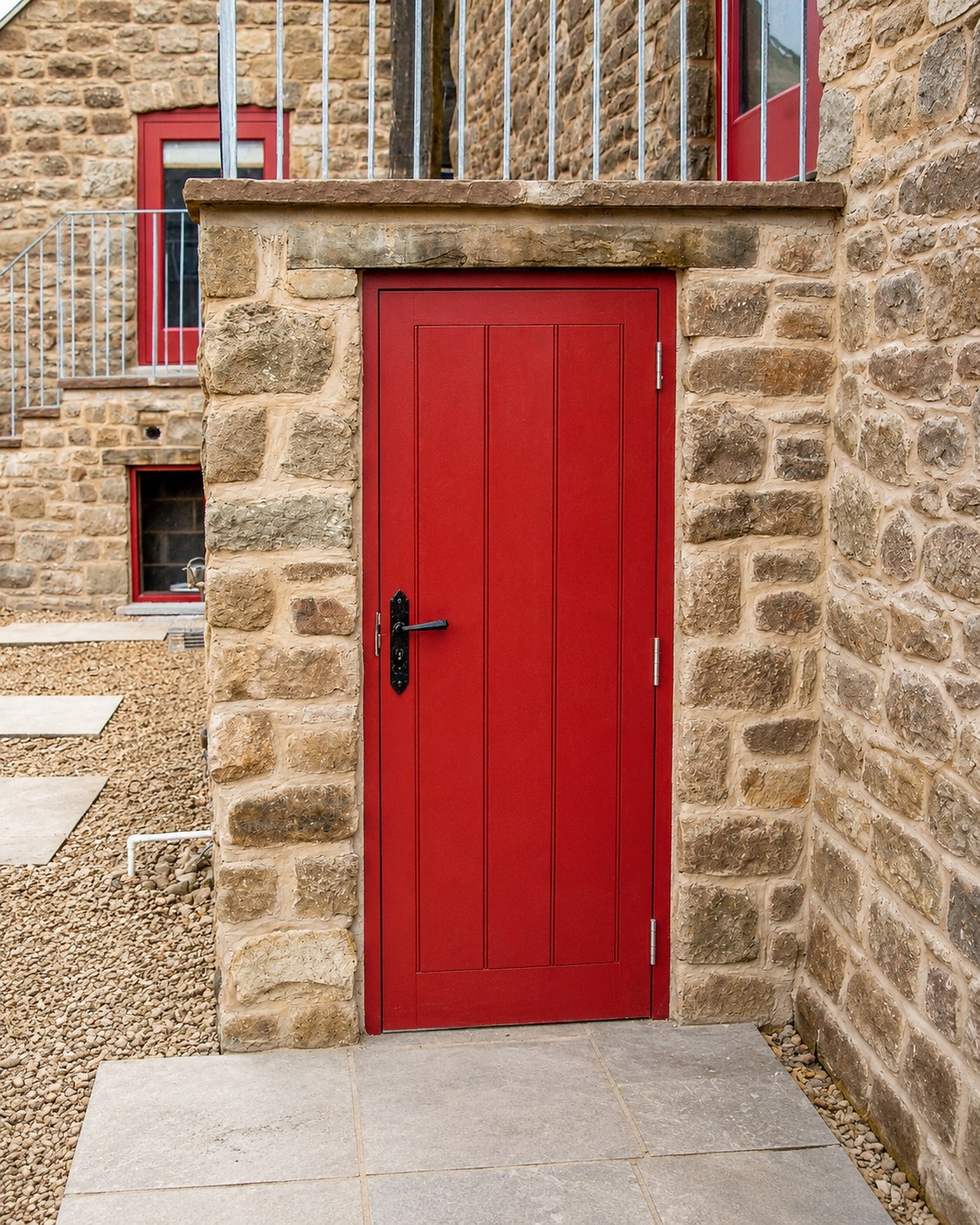 Red-painted boarded door below an external stair