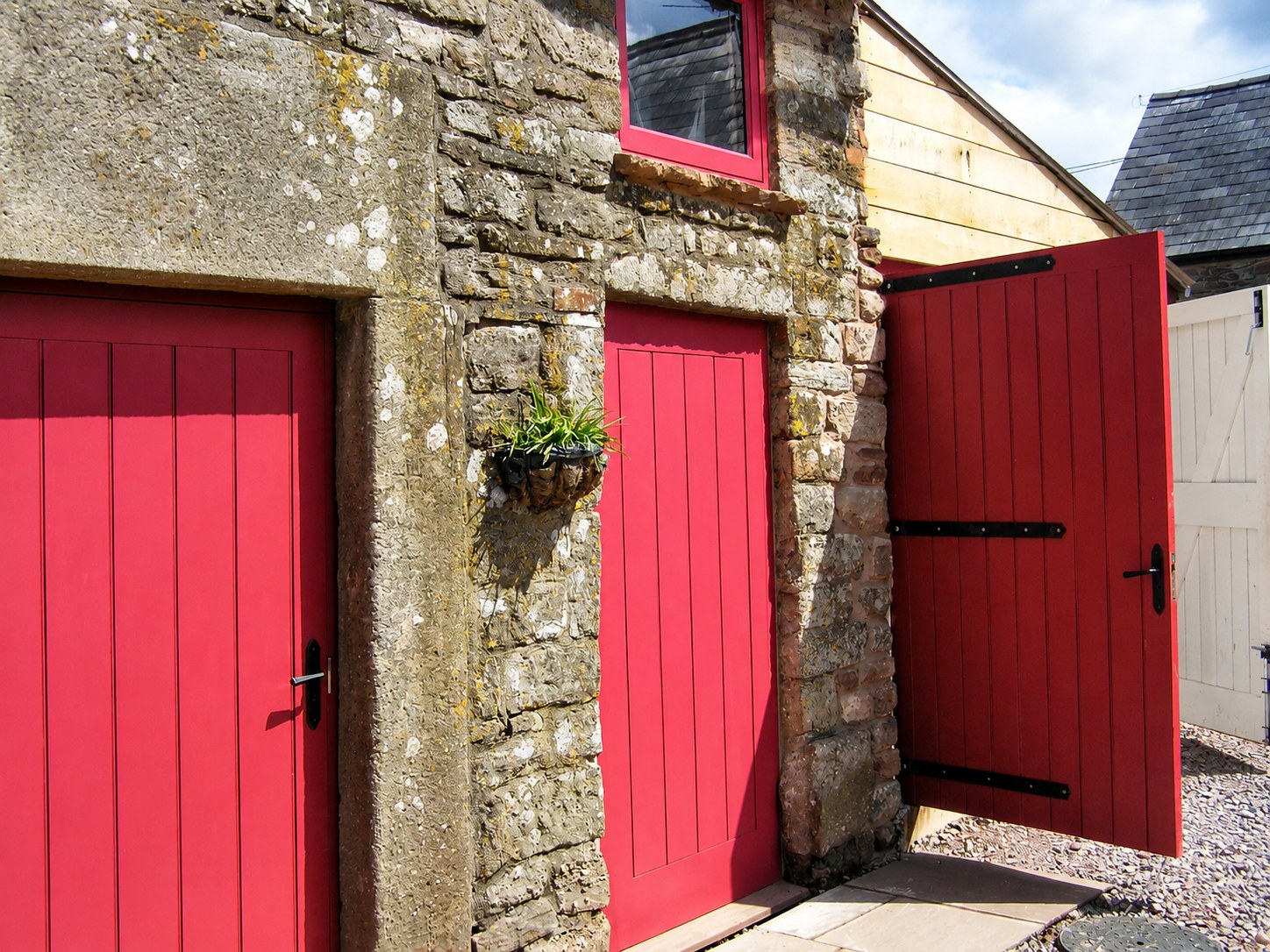 Red-painted timber doors to a stone outbuilding