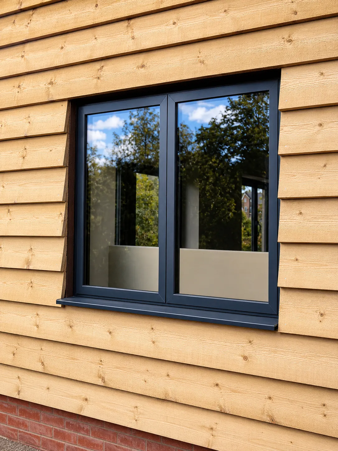 Closed grey aluminium casement in timber cladding