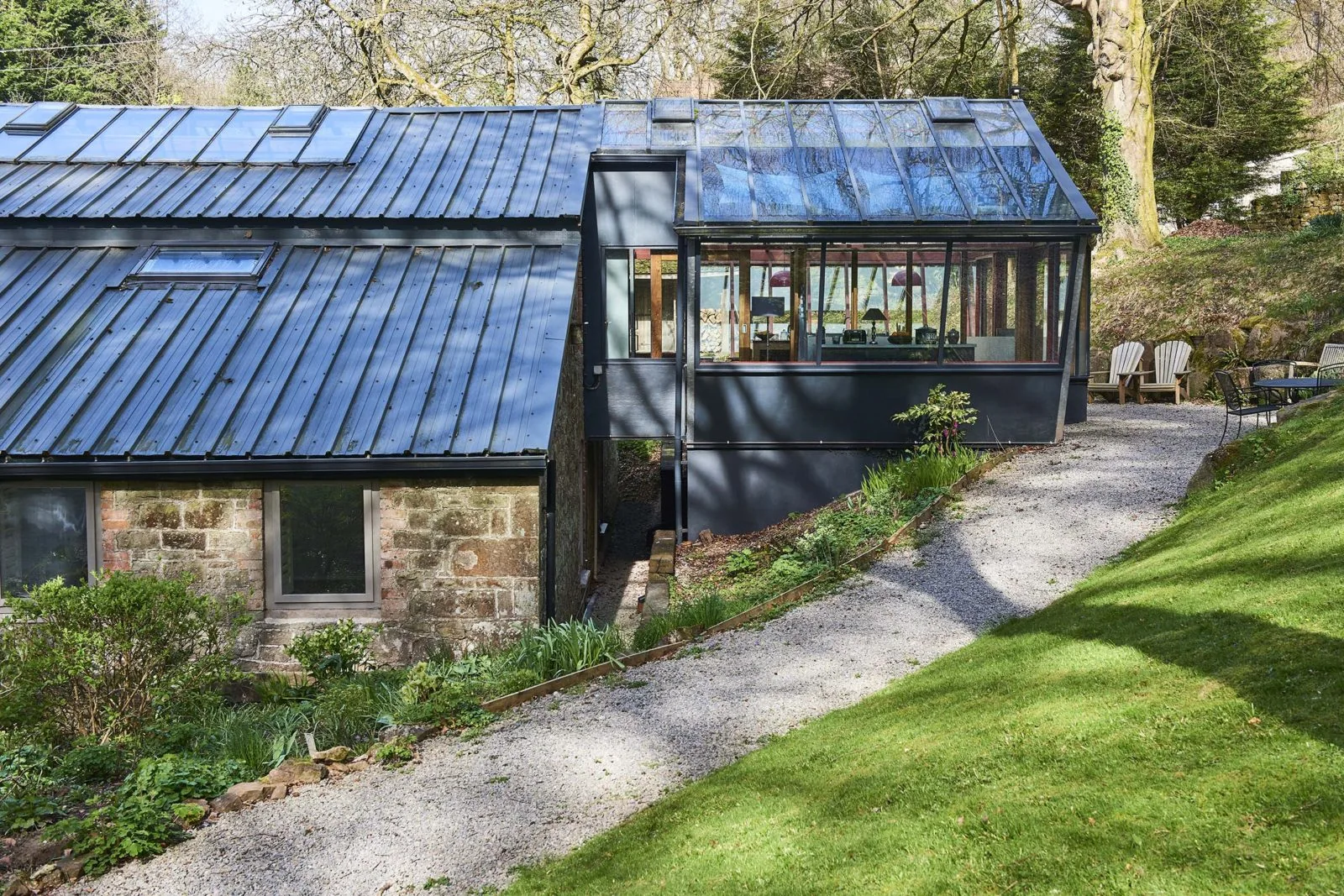 Glazed garden room beside a stone building