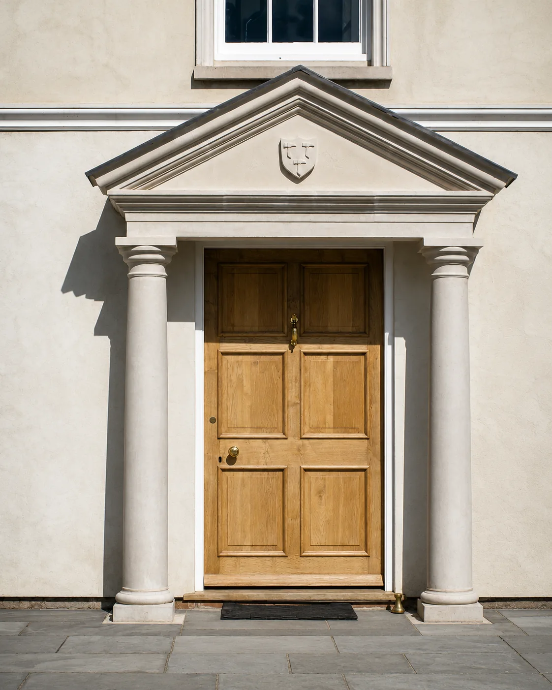 Natural timber entrance door below a stone pediment