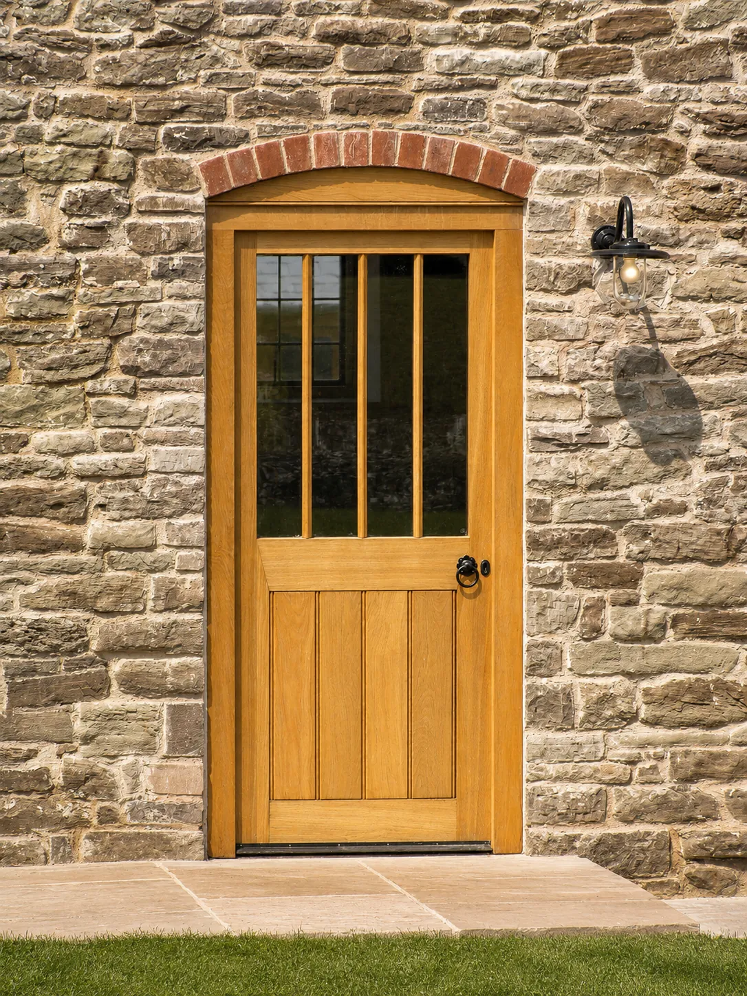 Glazed timber entrance door in an arched stone opening