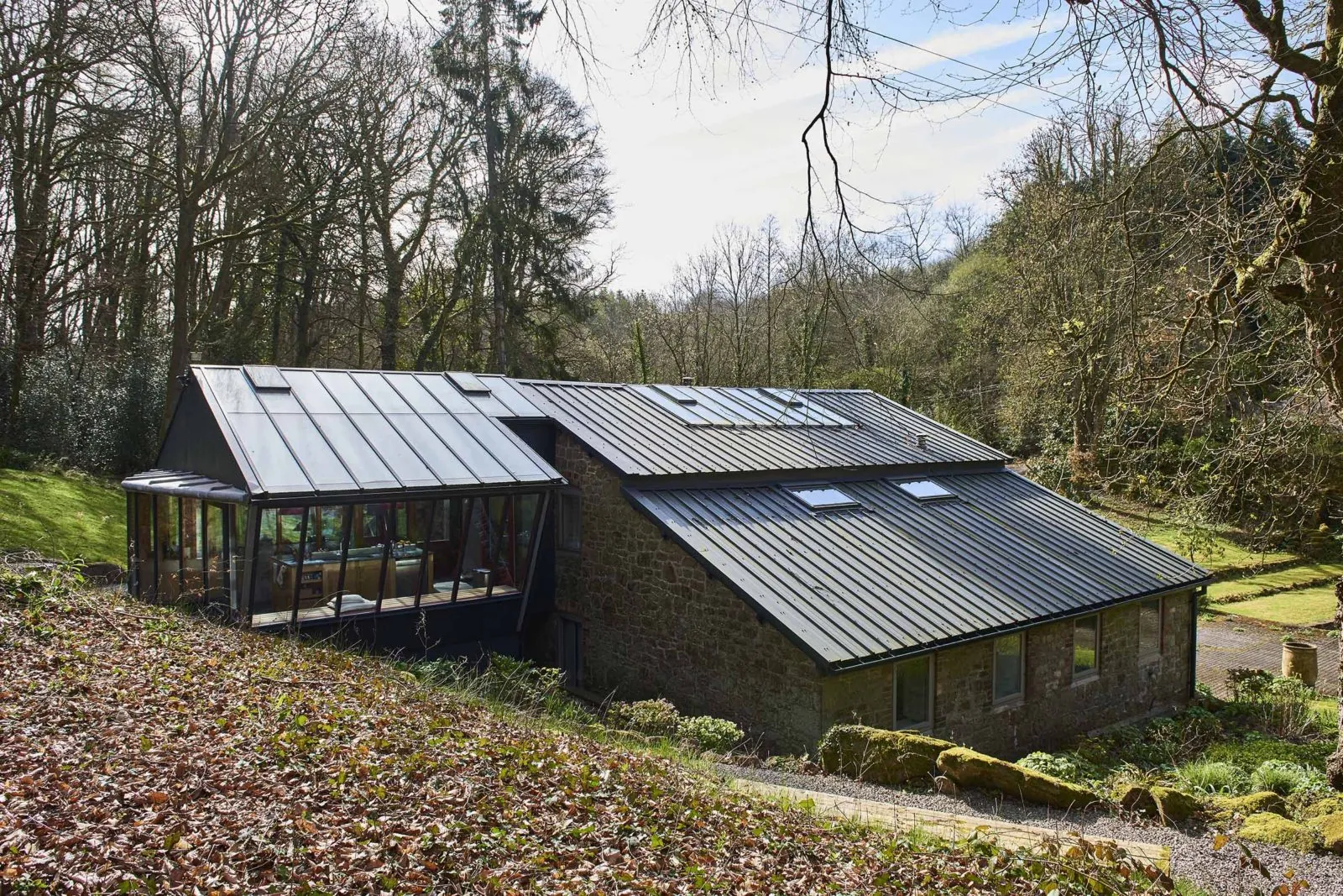 Glazed garden room and pitched roof beside a stone building