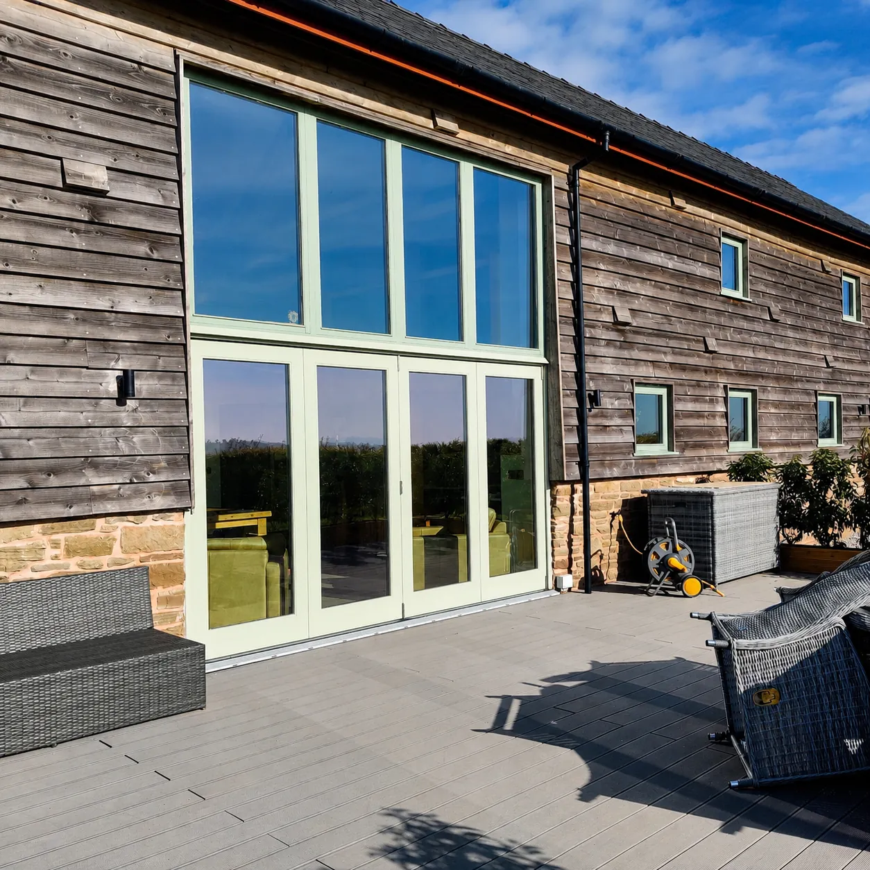 Full-height green painted glazed screen in a timber barn